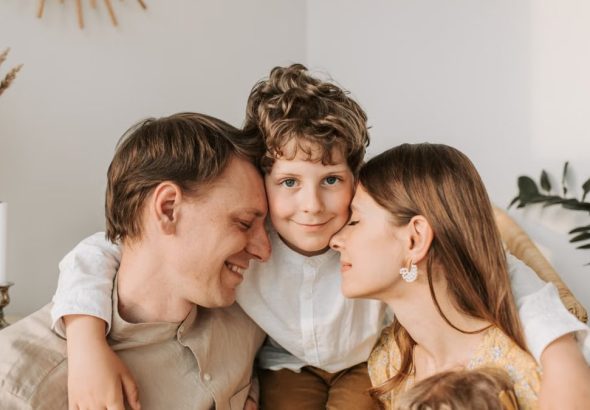 A joyful family moment with parents and their son embracing indoors.